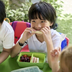 Young Asian school boy eating his baon during recess.