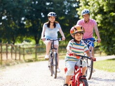 Young Asian family of three go biking at a park to prevent child obesity.