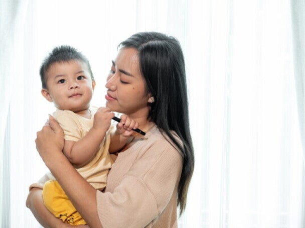 A Filipino mom carrying her child, worrying about getting her solo parent ID.