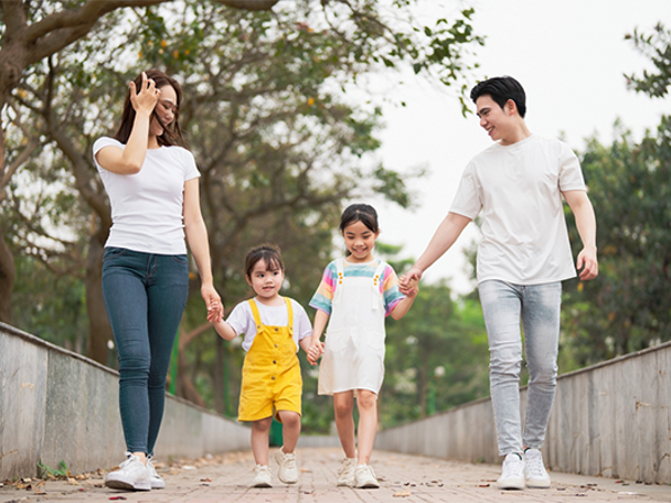 A young Asian single mom and man walk with two young children.