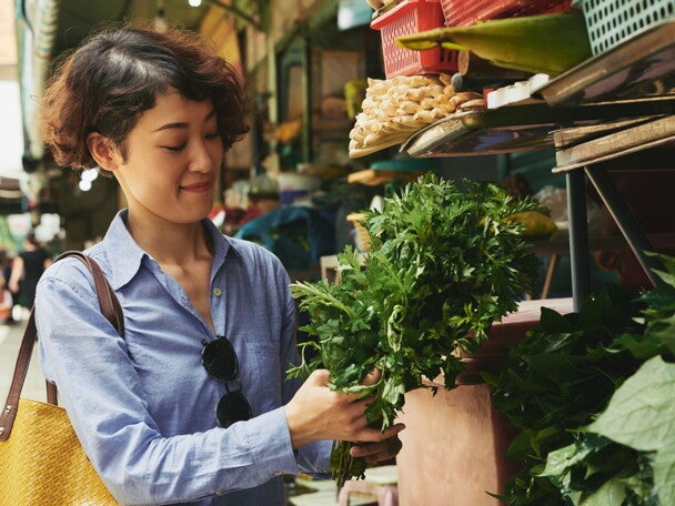 Asian woman buying vegetables at the wet market and thinking of budget ulam ideas to fit ₱500 