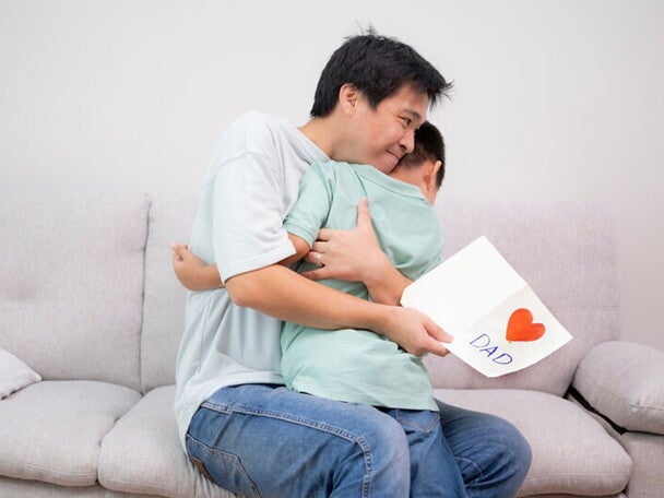 Asian dad hugs son after receiving a Father's Day card