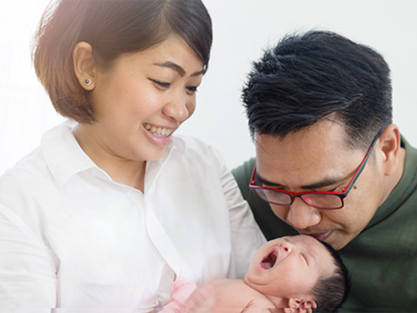 Asian mom and dad holding their newborn baby, thinking of baby boy names with meaning