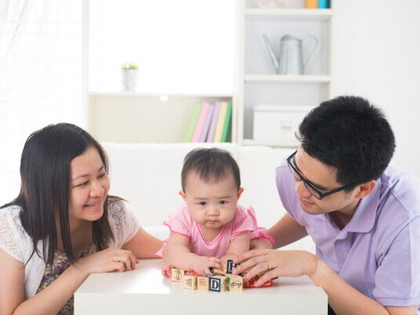 Young Asian parents spending quality time and playing with their little girl in the living room.