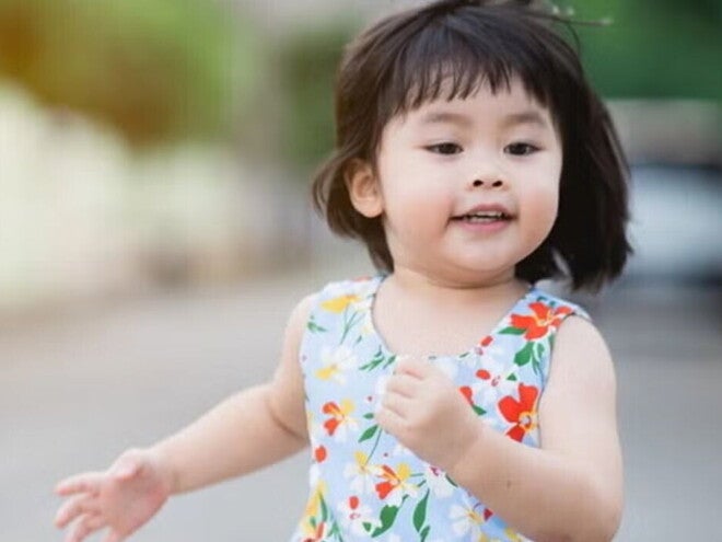 Asian female toddler runs in the street during summertime. Asian female toddler runs in the street during summertime.