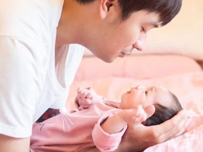 Young Filipino dad talks to his newborn while putting them down. Young Filipino dad talks to his newborn while putting them down.