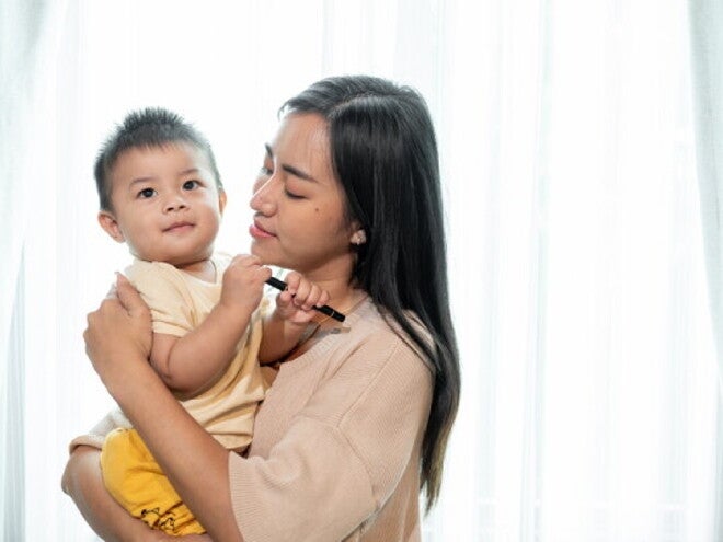 A Filipino mom carrying her child, worrying about getting her solo parent ID.