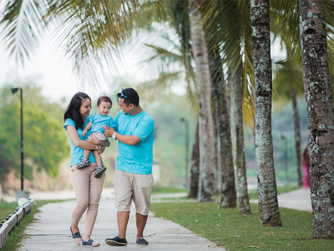 A young Asian couple with their child strolling at a park during one of the 2026 Philippine holidays.
