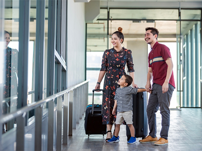 A young Asian mom, dad, and little boy at the airport with suitcases, getting ready to create memories through family travel. A young Asian mom, dad, and little boy at the airport with suitcases, getting ready to create memories through family travel.