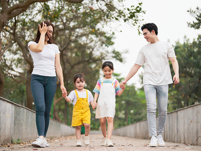 A young Asian single mom and man walk with two young children. A young Asian single mom and man walk with two young children.