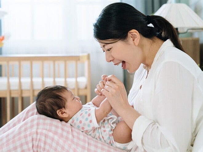 A young Asian woman sings a Filipino nursery rhyme or lullaby to a baby lying on her lap. A young Asian woman sings a Filipino nursery rhyme or lullaby to a baby lying on her lap.