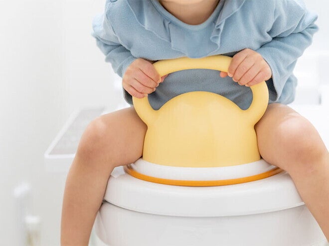 An Asian child sits on a toilet bowl with a potty training seat. An Asian child sits on a toilet bowl with a potty training seat.