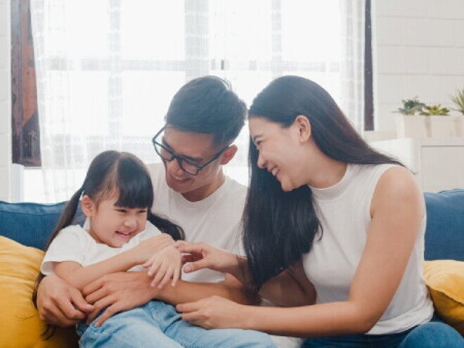 An Asian couple with their little girl on the sofa at home, a picture of family love.