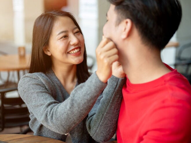 Young Asian woman pinches her partner's cheeks as they talk responsible parenthood. 