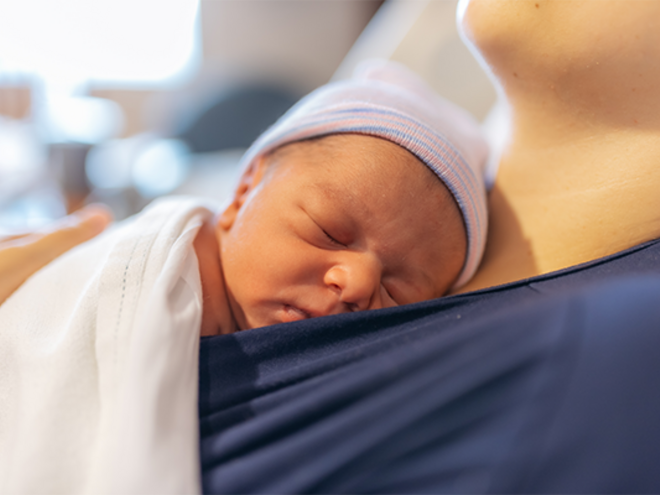 A mom holding her premature baby in the hospital, doing kangaroo mother care for skin-to-skin contact.
