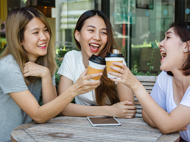 Happy Asian women friends sitting in a cafe, drinking coffee and talking together as a support system.