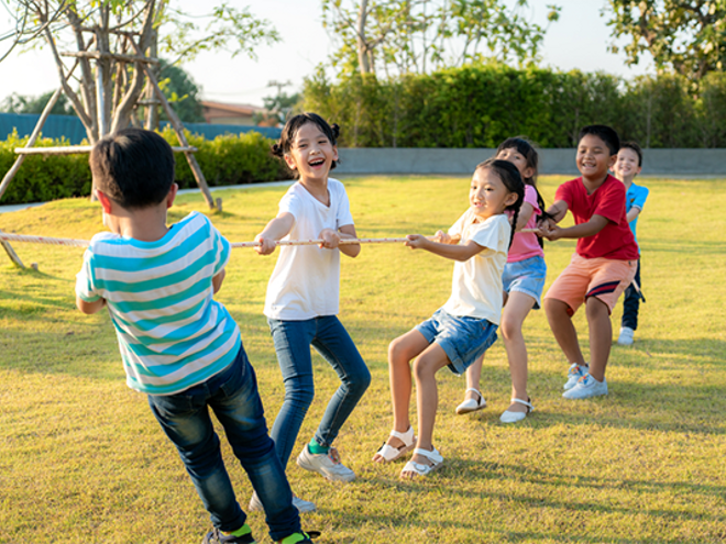 Asian children of mixed genders play tug-of-war outdoors Asian children of mixed genders play tug-of-war outdoors