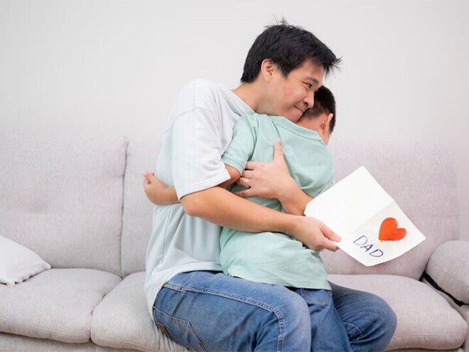Asian dad hugs son after receiving a Father's Day card Asian dad hugs son after receiving a Father's Day card