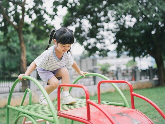 Asian girl, who doesn't show any signs of low calcium, climbs up the slide at a playground. Asian girl, who doesn't show any signs of low calcium, climbs up the slide at a playground.