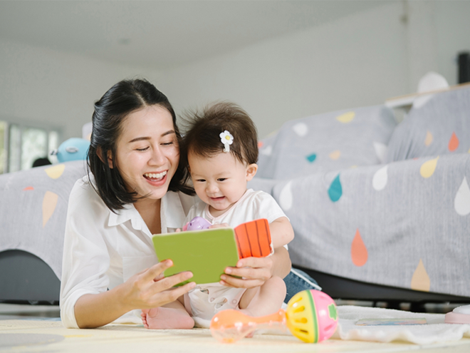 Asian mom and toddler daughter happily reading