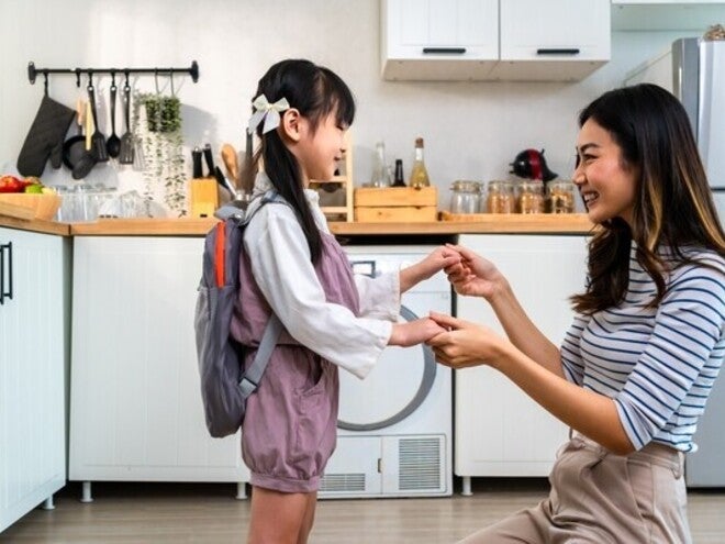 Asian mom holding little girl’s hand in the kitchen after giving her baon bag with milk products for school