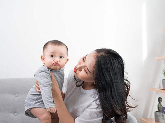 Asian mom playfully imitates her 1-year-old baby's pouting lips