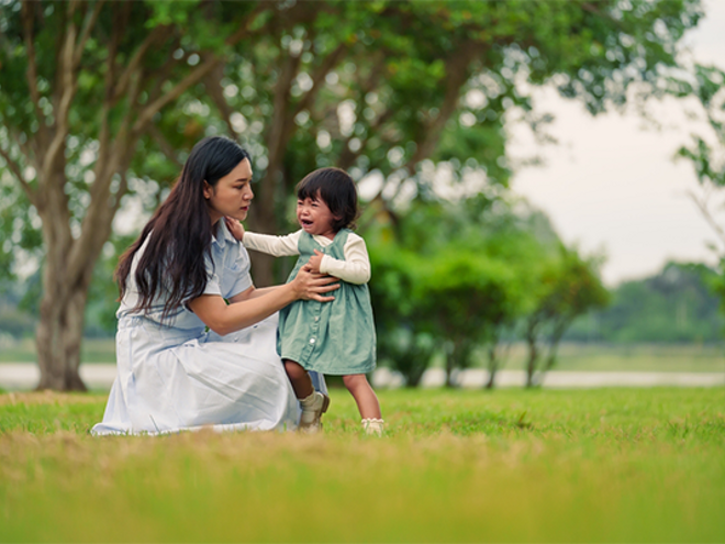 Asian mom trying to console her crying toddler