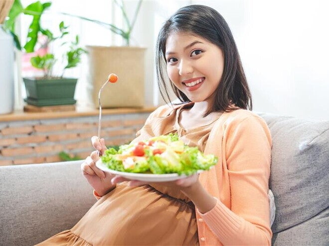 Asian pregnant woman holds a plate of vegetable salad for her dailly vitamin intake. Asian pregnant woman holds a plate of vegetable salad for her dailly vitamin intake.