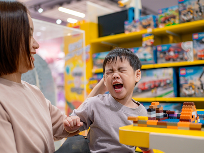Asian toddler becomes short-tempered while in a toy store with mom