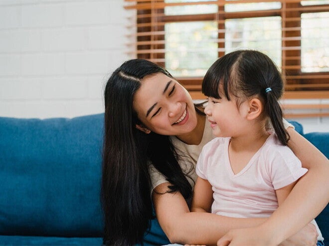Asian woman sits her child on her lap and looks at her lovingly after she had to discipline her Asian woman sits her child on her lap and looks at her lovingly after she had to discipline her