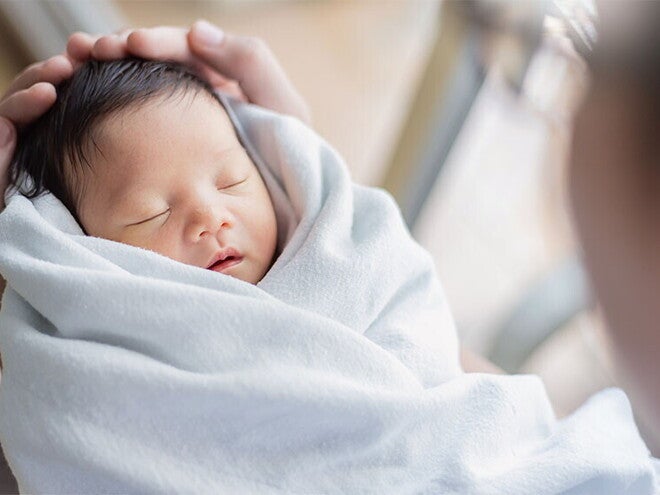 Closeup of healthy newborn in a swaddle being held by the father Closeup of healthy newborn in a swaddle being held by the father