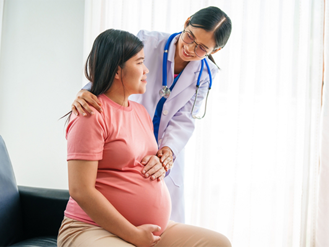 Doctor checks up on female patient who is 35 weeks pregnant.