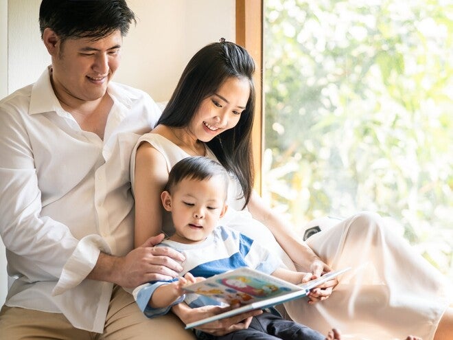 Filipino toddler reading a storybook in Tagalog with his parents.
