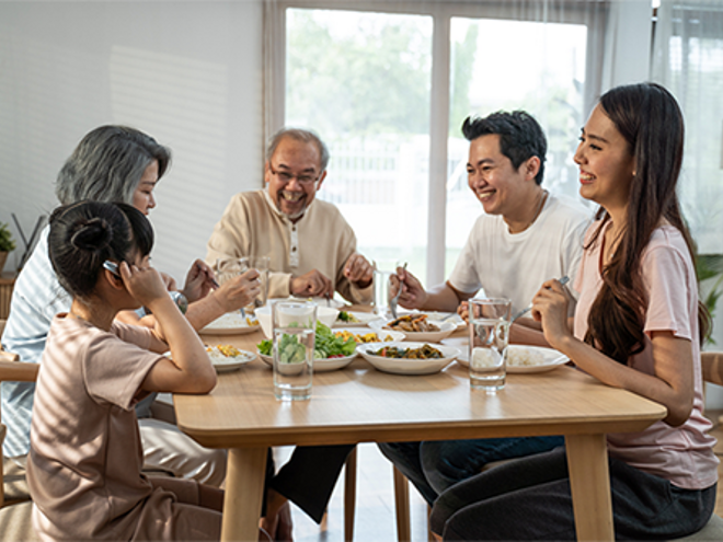 Healthy multigenerational Asian family sits down to eat a meal together