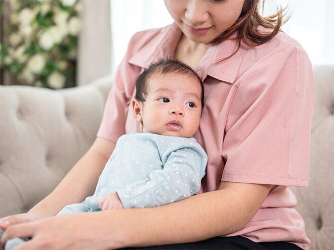 Mom holding newborn baby on couch Mom holding newborn baby on couch