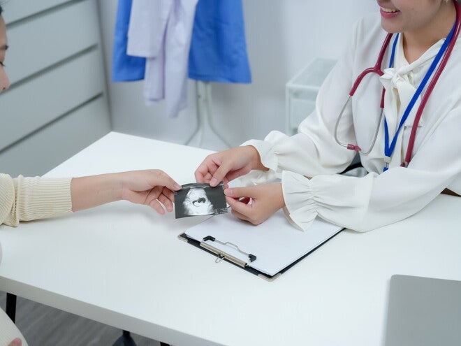 Pregnant Asian woman holding a ultrasound from her obgyn. Pregnant Asian woman holding a ultrasound from her obgyn.