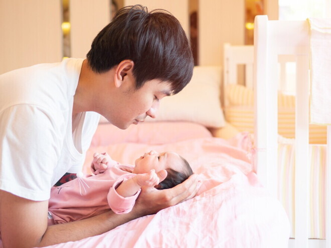 Young Filipino dad talks to his newborn while putting them down.