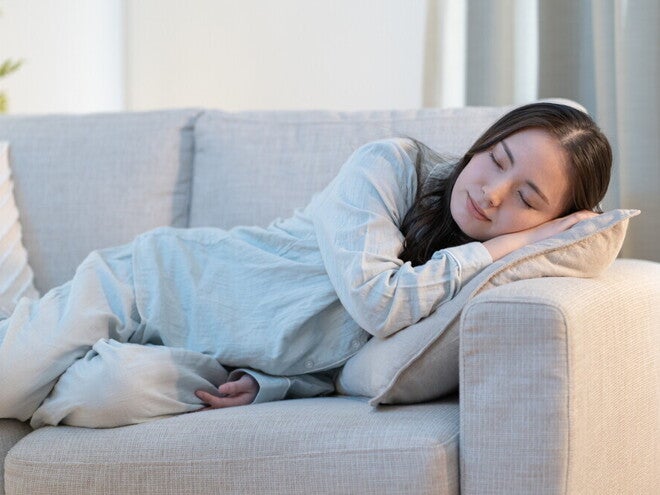 Recognizing Early Signs of Pregnancy Young Asian woman falls asleep on the sofa, exhibiting an early sign of pregnancy.