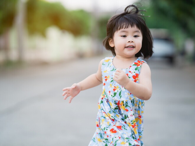 Asian female toddler runs in the street during summertime. Asian female toddler runs in the street during summertime.