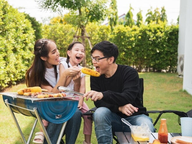 8 Simple Ways to Inspire Healthy Eating Habits in the Whole Family Asian family enjoying barbecued corn outdoors.