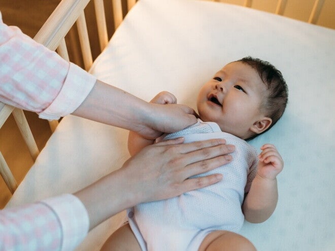 Baby Sleeping Position Basics Asian baby being put to sleep on their back in safe crib.