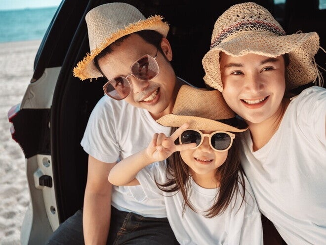 A young Asian couple and their preschooler daughter on a beach for a family trip out of town.