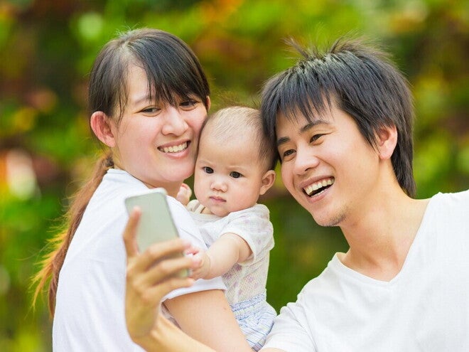 8 Meaningful Baby Monthly Milestone Ideas Asian couple takes a selfie with their baby.