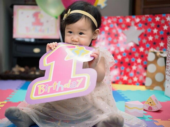 Little Asian baby girl celebrating her first birthday with a birthday party. 