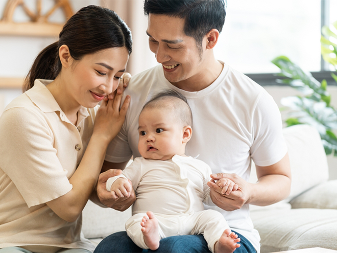 Smiling mother and father holding newborn son at home, considering birth control methods for family planning Smiling mother and father holding newborn son at home, considering birth control methods for family planning