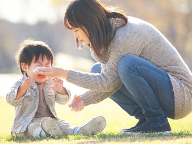 Asian mom comforts her little boy to help his emotional regulation as he cries outdoors.