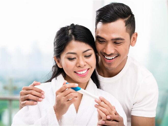 Young Asian woman is 1 month pregnant and surprises her husband with a positive pregnancy test. Young Asian woman is 1 month pregnant and surprises her husband with a positive pregnancy test.