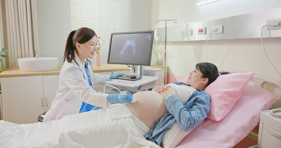 Asian doctor performs an ultrasound on a pregnant woman in a hospital bed. Asian doctor performs an ultrasound on a pregnant woman in a hospital bed.