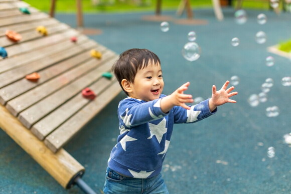 Male toddler plays with bubbles at a playground.