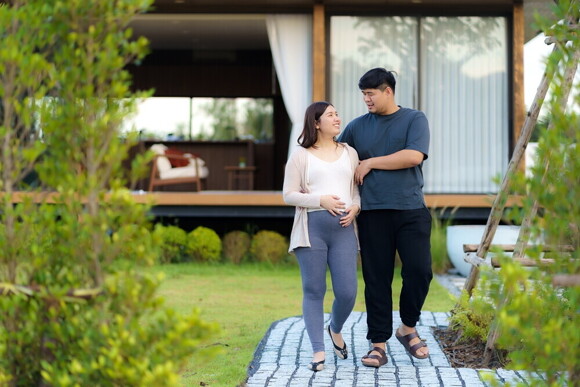 Pregnant Asian mom and husband discuss birth plans while taking a walk. Pregnant Asian mom and husband discuss birth plans while taking a walk.